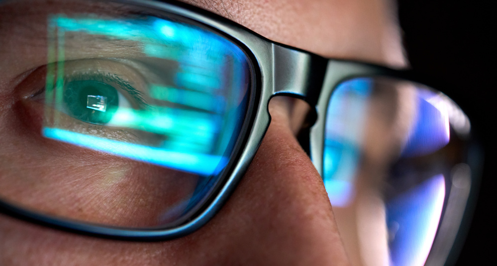 developer coder looking on computer, programming code reflecting in glasses.